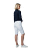 Woman wearing a navy sweater and white shorts on a plain background