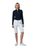 Woman wearing a navy long-sleeve top and white pants on a light gray background