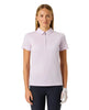 A woman modeling a pink short-sleeve polo shirt with a half-zip collar, paired with dark navy pants and a white golf glove, against a solid light gray background.