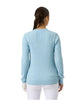 Woman wearing a light blue sweater and white pants on a plain background