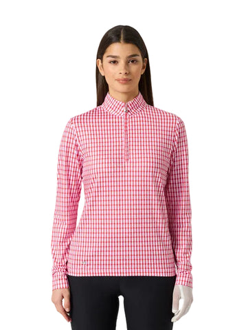 A woman modeling a pink and white gingham long-sleeve polo shirt with a half-zip collar, paired with black pants, against a light gray studio background.