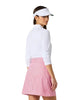 A woman modeling a white long-sleeve golf shirt, a pink and white gingham check skirt, a white visor, white socks, and white golf shoes against a light gray studio background.