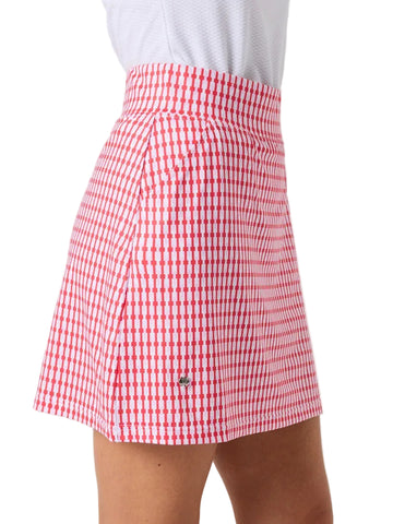 A close-up of a model wearing a red and white gingham patterned skirt with a small green crocodile logo near the bottom left hem, paired with a white top against a light gray background.