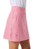 A close-up of a model wearing a red and white gingham patterned skirt with a small green crocodile logo near the bottom left hem, paired with a white top against a light gray background.