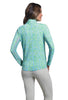 Woman wearing a green patterned long-sleeve shirt and beige pants on a white background
