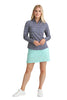 Woman wearing a patterned long-sleeve top and light blue skirt on a white background