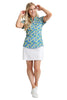 Woman wearing a colorful patterned shirt and white skirt on a light background