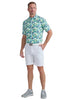 Man wearing a patterned shirt and white shorts on a gray background