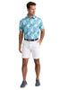 Man wearing a colorful floral shirt and white shorts on a light background