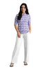 Woman wearing a purple floral blouse and white pants on a gray background