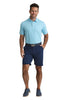 Man wearing a light blue patterned polo shirt and navy shorts on a white background