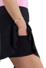 Person wearing a black skirt with a gold bracelet on a white background