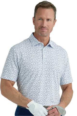 Man wearing a patterned polo shirt holding golf clubs against a plain background