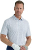 Man wearing a patterned polo shirt holding golf clubs against a plain background