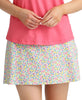 Person wearing a pink top and colorful floral skirt on a plain background