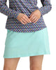 Person wearing a patterned long-sleeve top and light blue skirt on a plain background