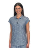 A woman modeling a short-sleeve polo shirt with a blue and white geometric pattern, featuring a half-zip collar, set against a plain white wall.