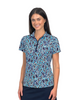 A woman modeling a short-sleeve collared polo shirt with an abstract geometric pattern in blue, navy, and white, paired with dark navy bottoms, set against a plain white background.