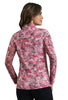 A woman shown from the back wearing a long-sleeve collared top with a pink, red, and black abstract floral pattern, paired with black pants, against a solid white studio background.