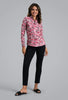 A woman modeling a long-sleeve quarter-zip pullover top with a pink, red, and black abstract pattern, paired with black pants and black slide sandals, against a solid grey studio background.