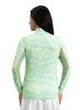 Woman wearing a light green and blue patterned long-sleeve top with a white skirt on a white background