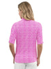 A woman viewed from the back wearing a bright pink short-sleeve button-up shirt with a white geometric pattern, paired with white pants, against a solid white studio background.