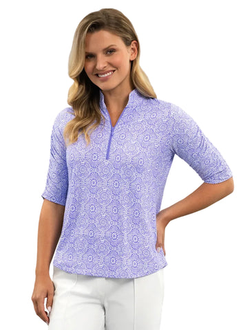 Woman wearing a purple patterned shirt and white pants on a white background