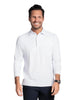 A smiling man wearing a white long-sleeve polo shirt and dark navy shorts, standing against a solid studio background.