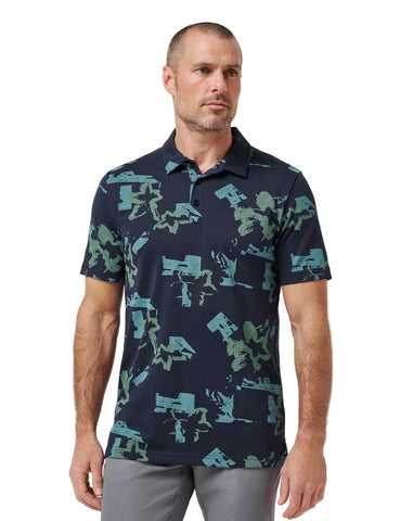 Man wearing a navy polo shirt with green camouflage pattern on a white background