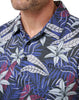 Close-up of a man wearing a patterned shirt with blue, white, and purple leaves.
