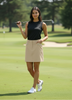 Woman holding a golf club on a golf course with trees in the background