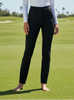 Woman standing on a golf course wearing a white top and black pants.