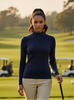 Woman in a navy blue sweater and beige pants standing on a golf course